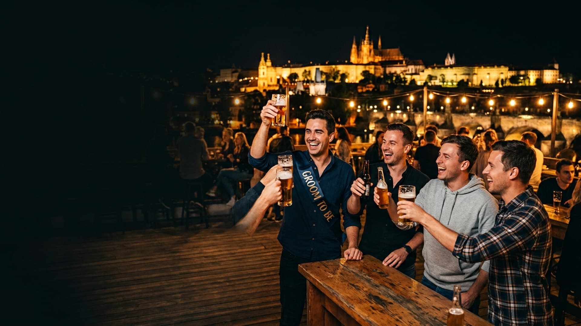 The groom in a sash toasting with his mates on a riverside terrace below the lit-up Prague Castle